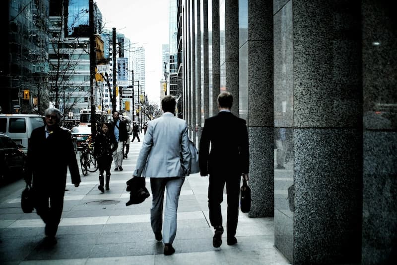 businessmen walking away down the sidewalk